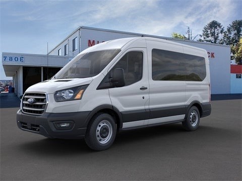 White Ford Transit passenger van parked in a paved lot.