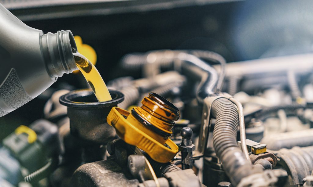 Engine oil being poured into a car engine during an oil change.